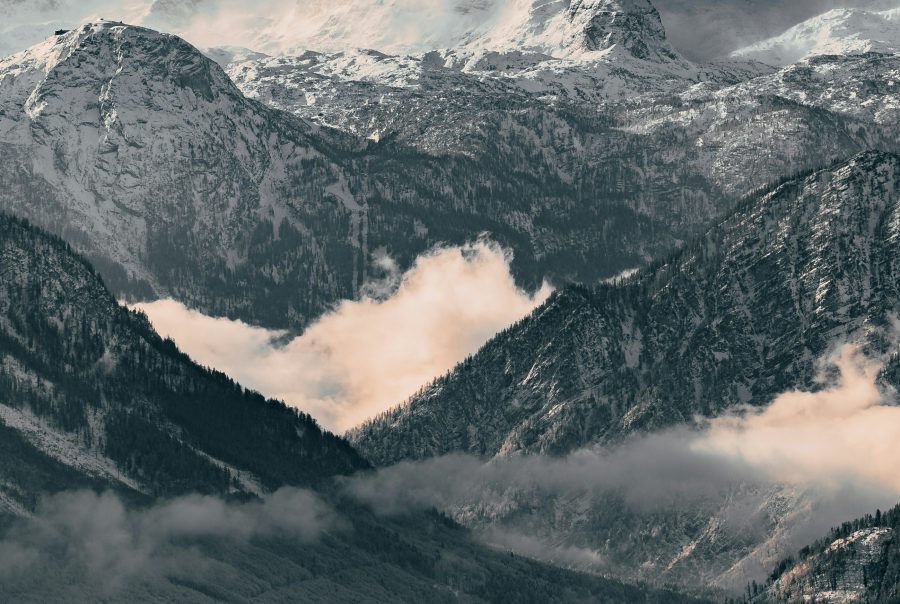Ein atemberaubender Blick auf die majestätischen Berge im Salzkammergut, umgeben von üppigen Wäldern und klaren Seen unter einem strahlend blauen Himmel.